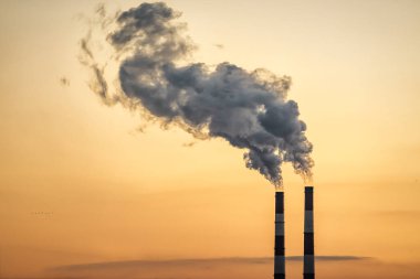 Sarı arka planda sigara içilen iki fabrika borusu. Sanayi teması