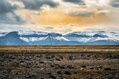 İzlanda 'da gün batımında karlı dağların olduğu çöl volkanik manzarası. Güzel manzara