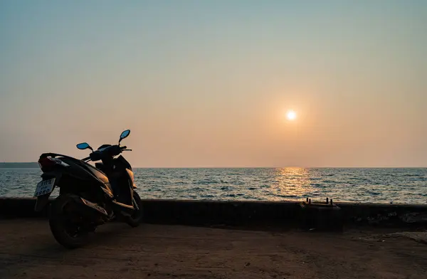 Silhouette: Tourist motorbikes parked on the seaside with the rising sun at Koh Mak, Trat Province, Thailand.