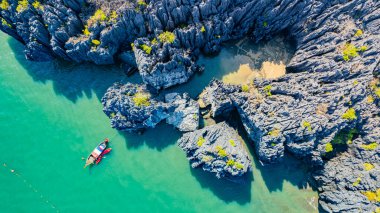 View of Prasat Hin Pan Yot, an island in the sea, with tourists rowing boats to visit the interior in Satun Province, southern Thailand, Asia. clipart