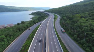 Nehir boyunca uzanan yüksek yol ve otoyol yağmur mevsiminde dağların güzel kıvrımları boyunca esiyor, Lam Takhong Barajı 'nın her iki tarafında yeşil ağaçlar, Nakhon Ratchasima