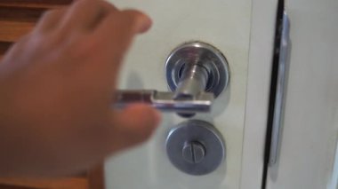 Bir insanın eli kapıyı açmak için kapı kolunu çeviriyor..