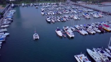 Limanda demirlemiş bir sürü lüks teknesi ve limana girip çıkan tekneleri olan bir yat marinası..