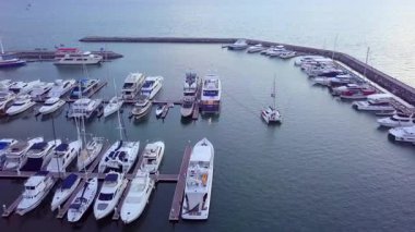 Limanda demirlemiş bir sürü lüks teknesi ve limana girip çıkan tekneleri olan bir yat marinası..
