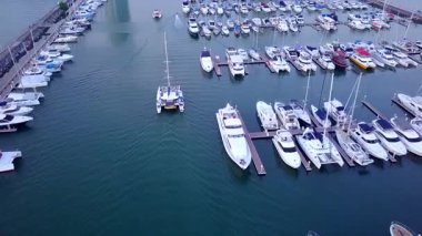 Limanda demirlemiş bir sürü lüks teknesi ve limana girip çıkan tekneleri olan bir yat marinası..