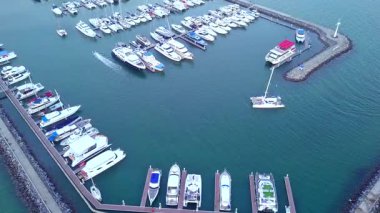 Limanda demirlemiş bir sürü lüks teknesi ve limana girip çıkan tekneleri olan bir yat marinası..