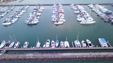 Limanda demirlemiş bir sürü lüks teknesi ve limana girip çıkan tekneleri olan bir yat marinası..