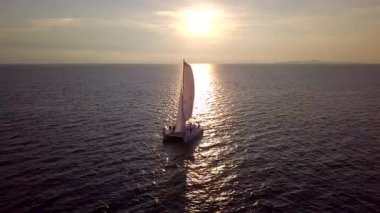 Gün batımında bir yat denizde yelken açar..