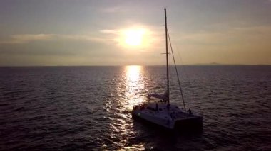 Gün batımında bir yat denizde yelken açar..