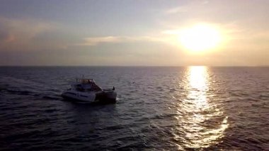 Gün batımında bir yat denizde yelken açar..