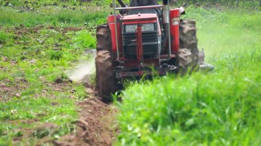 Çiftçiler çiftçilik için tarlayı sürmek için traktör kullanıyorlar..