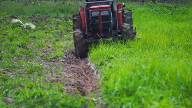 Çiftçiler çiftçilik için tarlayı sürmek için traktör kullanıyorlar..