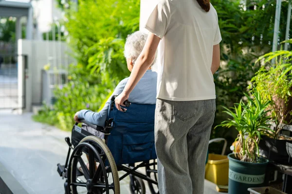 Caregiver help and care Asian senior or elderly old lady woman patient sitting on wheelchair to ramp in nursing hospital, healthy strong medical concept.