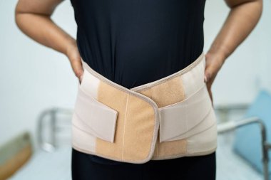 Asyalı kadın hasta sırtını, belini ve ortopedik bel kemiğini Walker 'la ağrıtıyor..