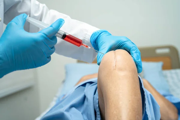 stock image Asian doctor inject Hyaluronic acid platelet rich plasma into the knee of senior woman to walk without pain.