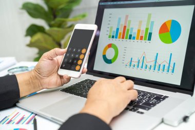 Modern ofis, finans ve iş konsepti grafikleriyle muhasebe projesini inceleyen Asyalı muhasebeci.