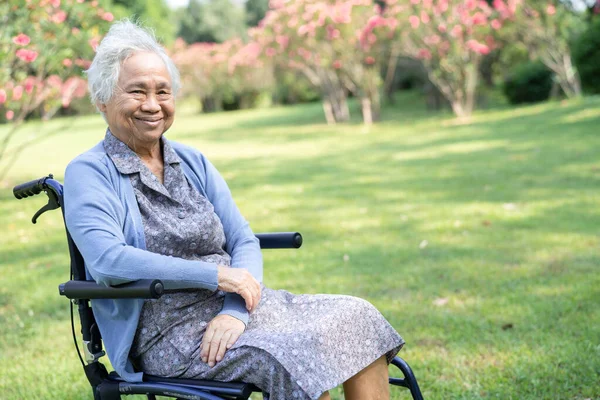 一位戴草帽的老年妇女坐在轮椅上在公园里旅行 — 图库照片
