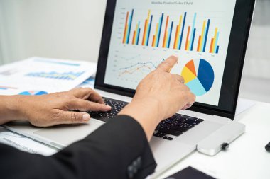 Modern ofis, finans ve iş konseptinde grafik grafik grafiği ve hesap makinesiyle çalışan ve finansal raporları analiz eden Asyalı muhasebeci.