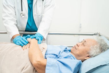 Doktor, hastanede sevgi, ilgi, cesaret ve empati gösteren yaşlı kadın hasta Asyalı yaşlılarla el ele tutuşuyor..