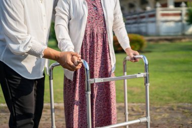Asya 'lı yaşlı ve yaşlı kadınlara yardım ve yataklık etmek için parkta yürürken sağlıklı bir şekilde yürüyen yaşlı kadın kullanılıyor..