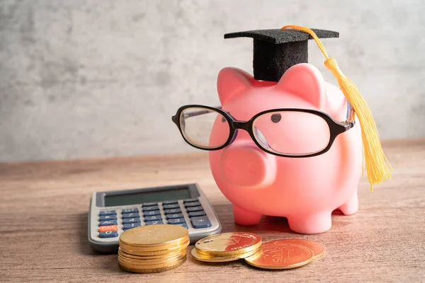 Pigging bank wearing eyeglass with coins and graduation hat; saving bank education concept.