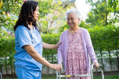 Doktor yardım ve bakım Asyalı yaşlı yaşlı ya da yaşlı kadın sağlıklı bir şekilde parkta yürürken yürüyüş yapıyor..