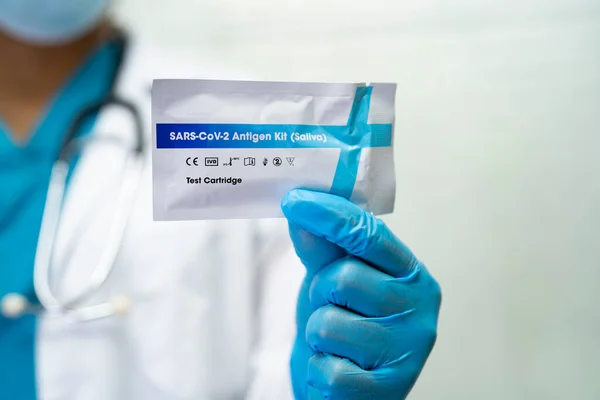Asian doctor holding Saliva Antigen Test Kit for check Covid-19 coronavirus in hospital.