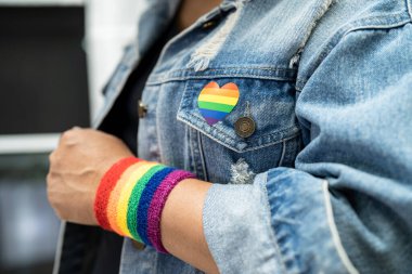 Gökkuşağı bileklik takan Asyalı kadın, beyaz arka planda kırpma yolu ile izole edildi, LGBT gurur ayının sembolü, Haziran sosyal ortamında gey, lezbiyen, biseksüel, transseksüel, insan hakları kutlamaları.