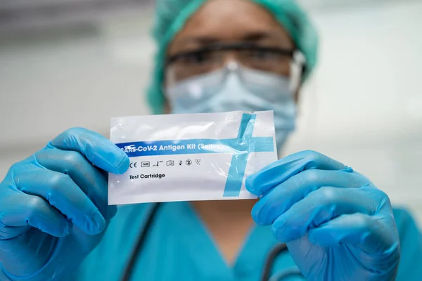 Asian doctor holding Saliva Antigen Test Kit for check Covid-19 coronavirus in hospital.