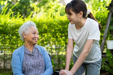 Caregiver help and care Asian elderly woman use walker with strong health while walking at park in happy fresh holiday.