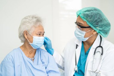 Doctor checking Asian senior woman patient wearing a face mask in hospital for protect Covid19 Coronavirus.
