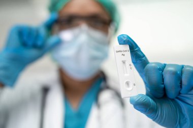 Asian doctor holding Saliva Antigen Test Kit for check Covid-19 coronavirus in hospital.