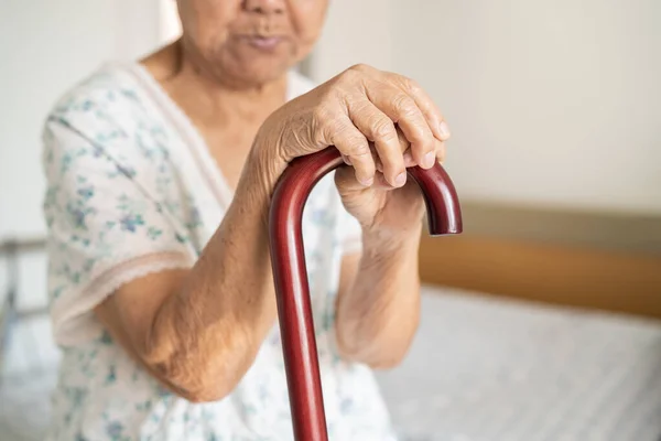 Asian elderly disability woman holding waling stick, wood cane, round handle, walking aid for help to walk.