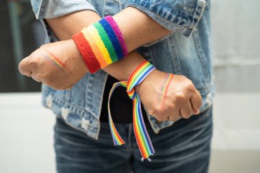 Gökkuşağı bileklik takan Asyalı kadın, LGBT onur ayının sembolü olarak beyaz arkaplanda izole edildi. Haziran sosyal ortamında eşcinsel, lezbiyen, biseksüel, transseksüel, insan hakları kutlanıyor..
