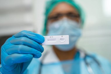 Asyalı doktor, Covid19 Coronavirus 'u kontrol etmek için tükürük antijen test kiti tutuyor..