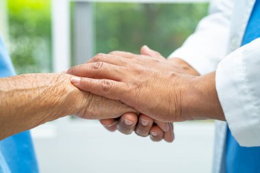 Caregiver holding hands Asian elderly woman patient with love, care, encourage and empathy at nursing hospital, healthy strong medical concept.