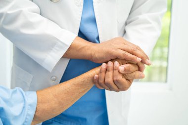 Caregiver holding hands Asian elderly woman patient with love, care, encourage and empathy at nursing hospital, healthy strong medical concept.