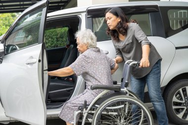 Caregiver help and support asian elderly woman sitting on wheelchair prepare get to her car to travel in holiday.