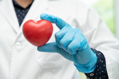 Hastane koğuşunda kırmızı kalp tutan bir doktor, sağlıklı güçlü tıbbi konsept..