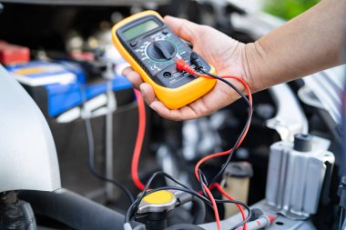 Yol kenarındaki bozuk arabanın kaputunun altında tamir için Asyalı oto tamircisi kontrolü..