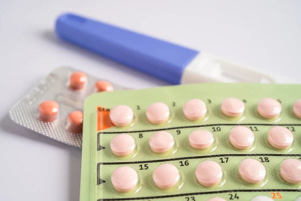 Pregnancy test and birth control pills on calendar, contraception health and medicine.