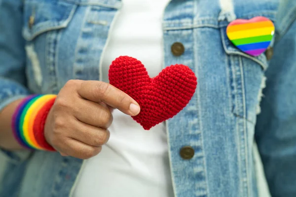 亚洲女人戴着彩虹旗腕带 手持红心 象征男女同性恋 双性恋 变性者自豪月 每年六月庆祝男女同性恋 双性恋 变性者 人权社会日 — 图库照片