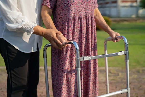 护理员帮助亚洲老年妇女与步行者在公园散步 健康有力的医疗理念 — 图库照片