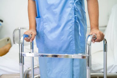 Asyalı hasta yürümeyi desteklemek için hastanede Walker kullanıyor..