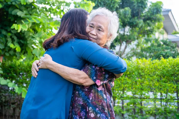 stock image Asian elderly woman hug with her daughter with love, care, help, encourage and empathy at park, healthy strong medical concept.