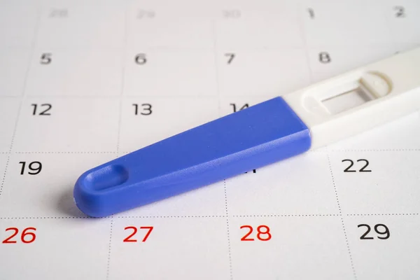 Pregnancy test on calendar, contraception health and medicine.