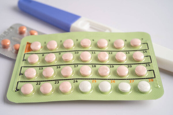 Pregnancy test and birth control pills on calendar, contraception health and medicine.