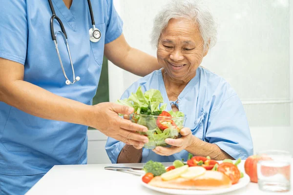 stock image Asian elderly woman patient eating salmon steak breakfast with vegetable healthy food in hospital.