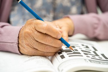 Alzheimer hastalığı AD, Asyalı yaşlı kadın bunama için beyin eğitimi için sudoku bulmacası oynuyor.