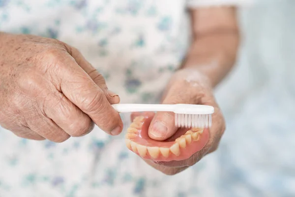 Asyalı Yaşlı Kadın Hasta Diş Fırçasıyla Takma Diş Protezini Temizliyor — Stok fotoğraf